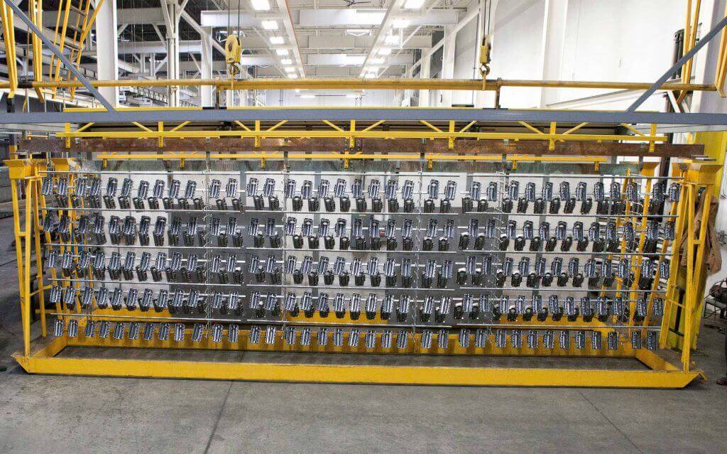 Zinc rack electroplating process showing large metal components mounted on racks being coated with zinc for corrosion resistance